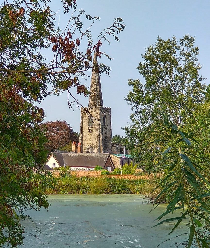 Church with tower and spire viewed across a lake