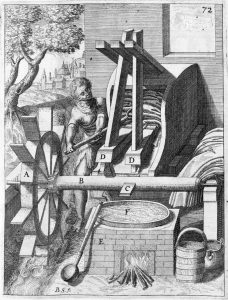 Engraving showing a person working at a fulling mill. A pan of liquid is bubbling over a fire. A waterwheel is driving a machine, into or out of which cloth is being taken.