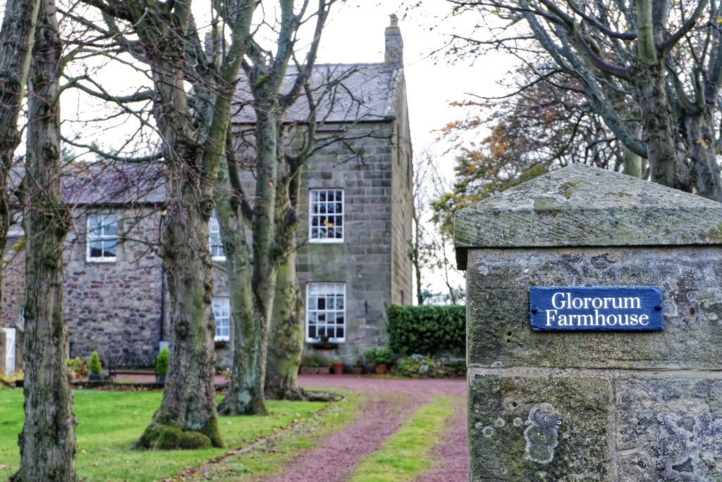 Gate post reading 'Glororum Farmhouse' with house in background