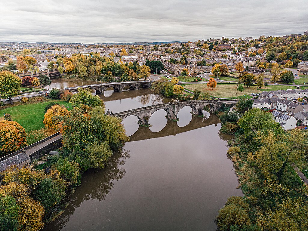 River spanned by two stone bridges, with a city in the background