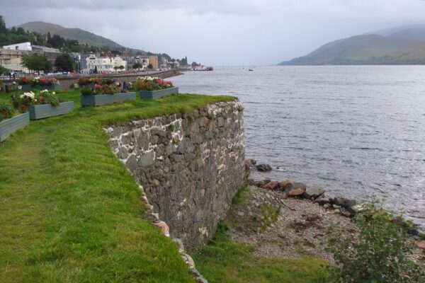 A sea wall overlooking water, with a town in the background