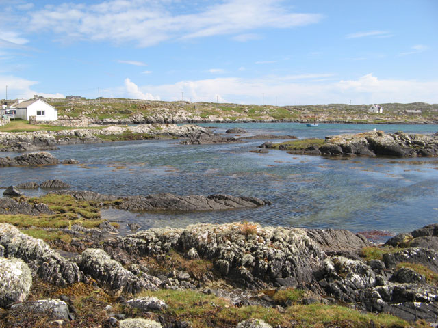 Rocky coastline with blue sea, small islets and a house